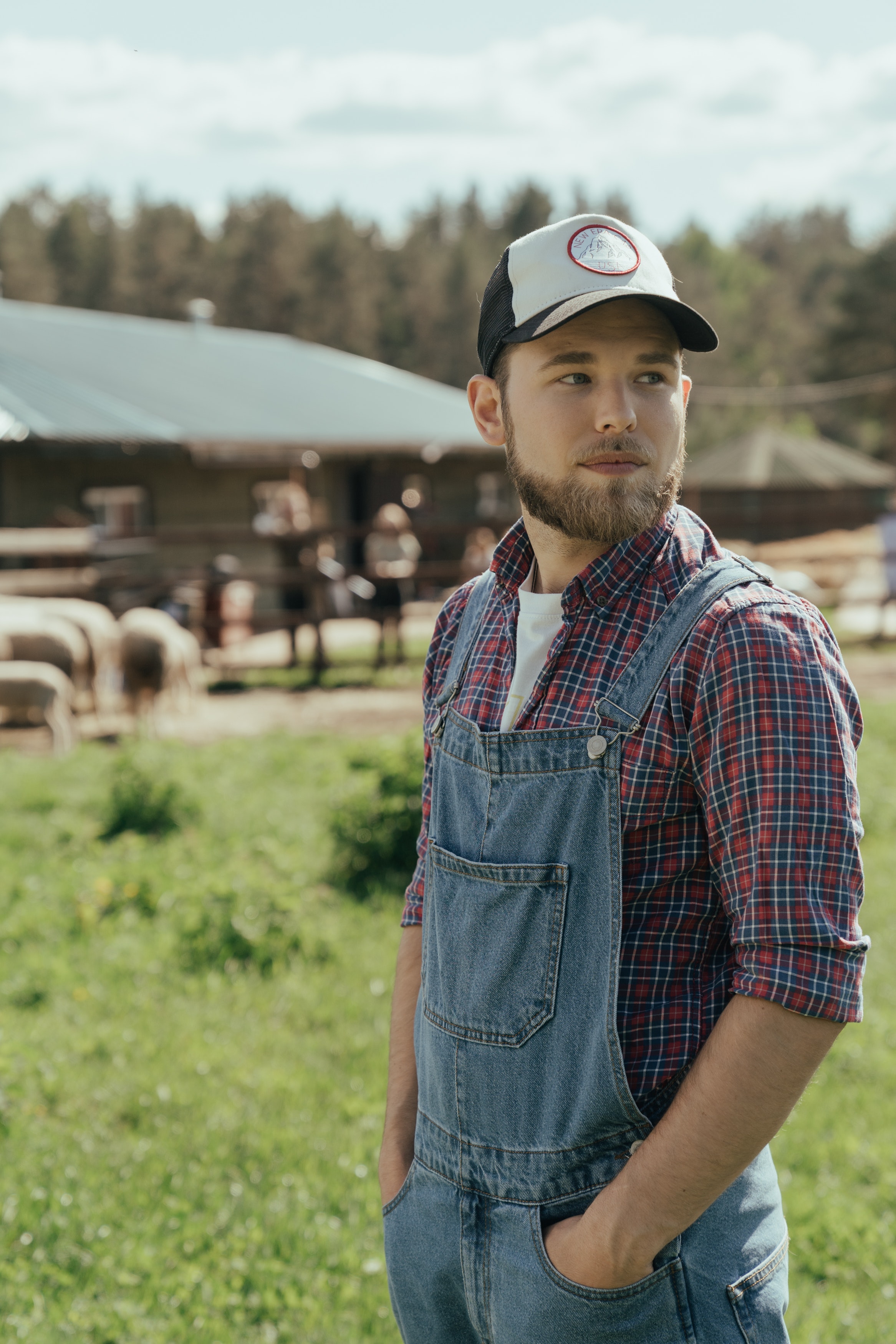  a man in overalls and a hat looking to the right of the camera