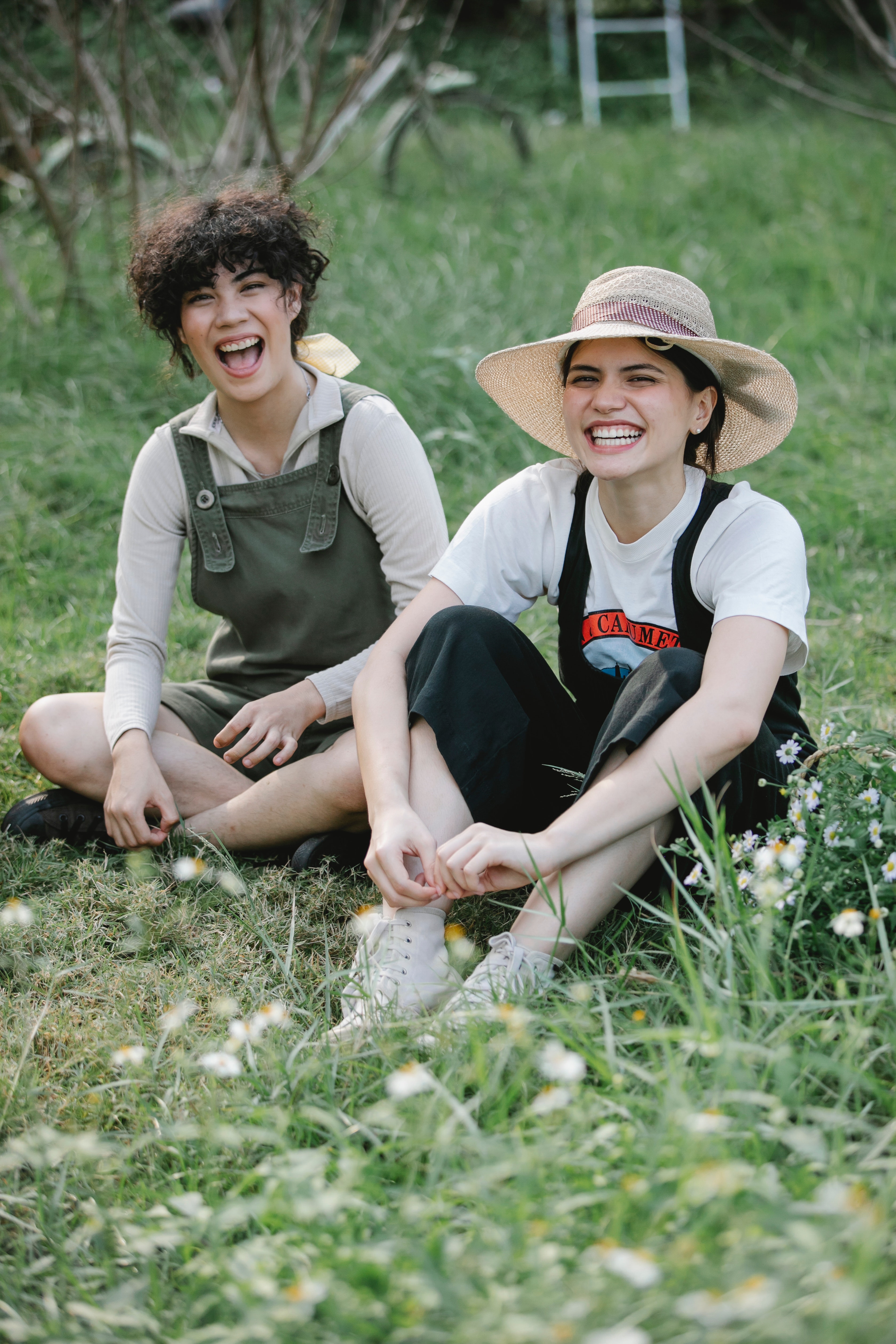 two women sitting in a field smiling and laughing
