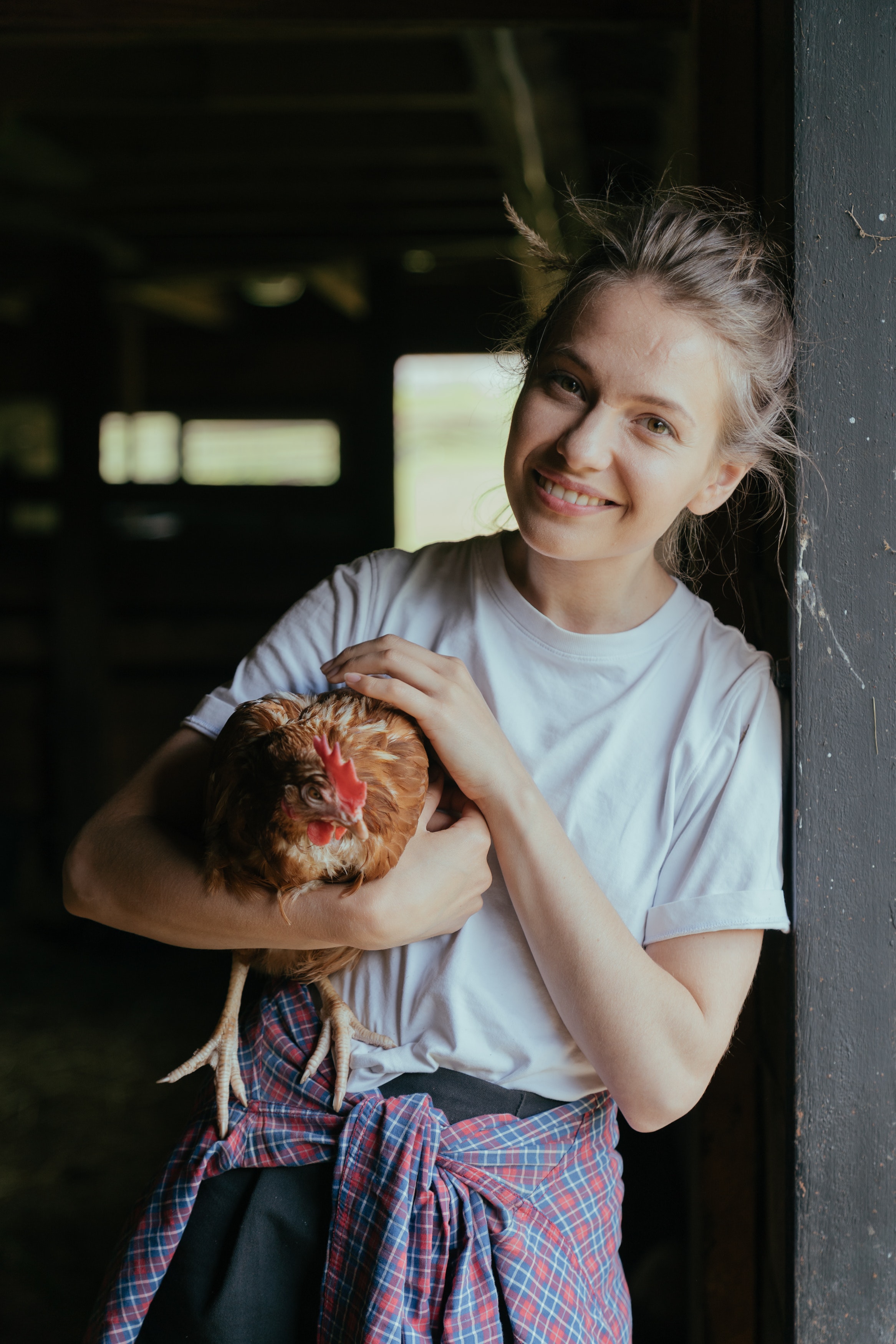 a woman holding a chicken and smiling at the camera