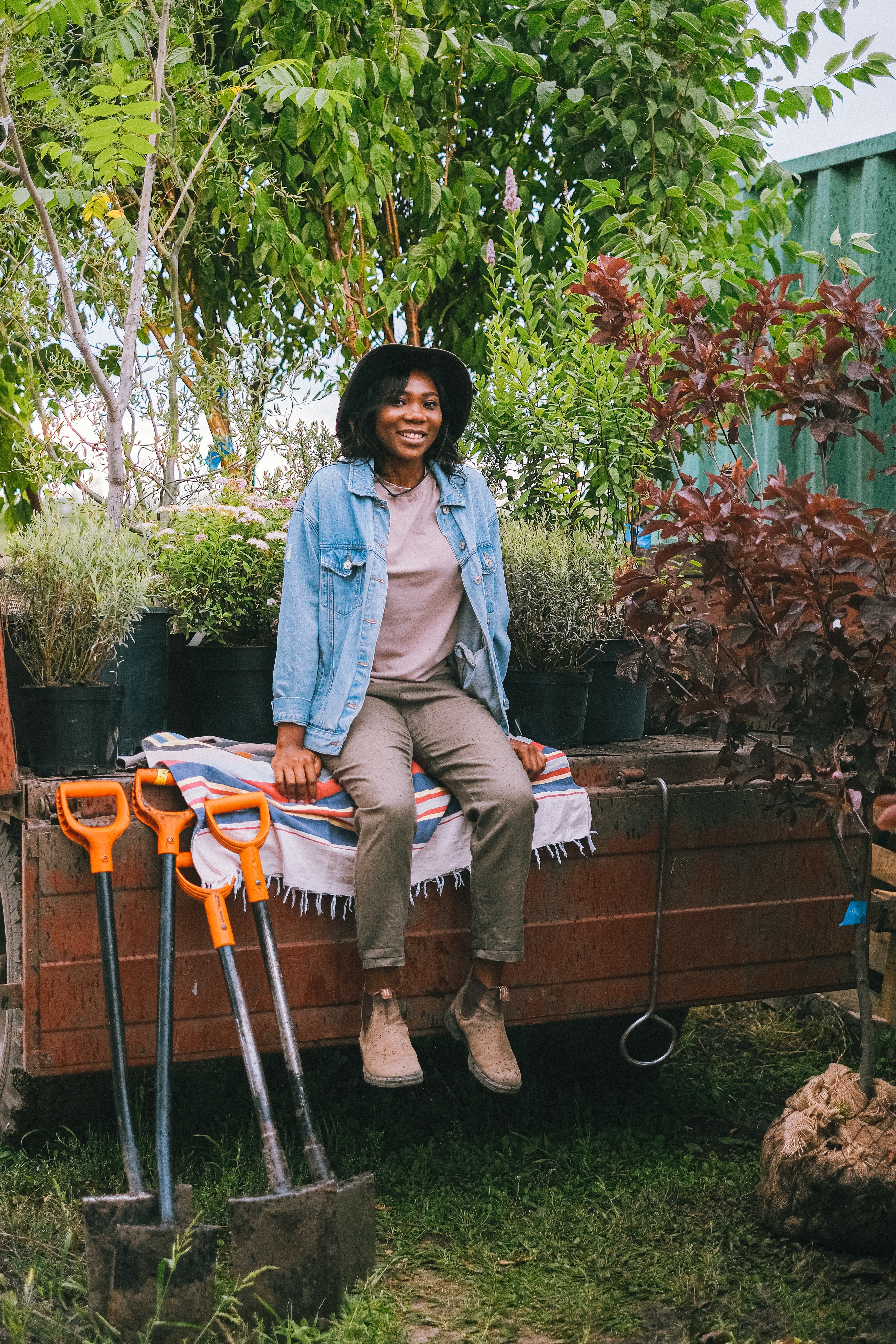 a woman sitting down out on a garden box out in the garden